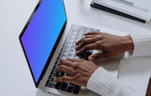 MacBook Pro mockup on a white table with glass of water at the side