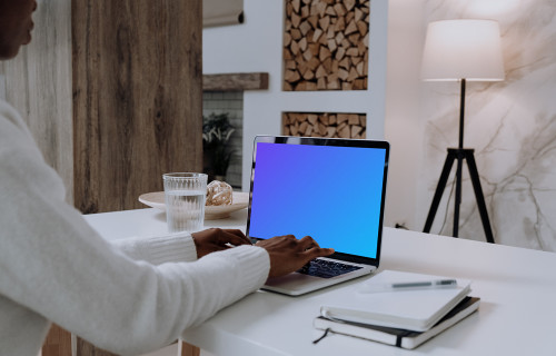 MacBook Pro mockup on white table with notebook by the side