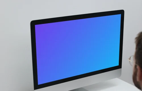 Homme travaillant sur son iMac sur une table blanche mockup