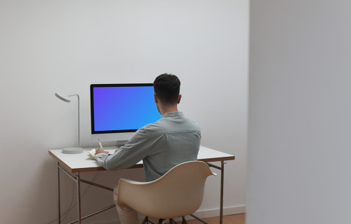 Man working on his iMac with his back to the camera