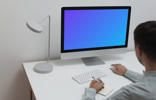 Mockup user using an iMac and writing into a notepad