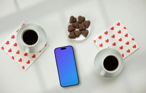 Smartphone mockup avec deux cafés et des chocolats en forme de cœur