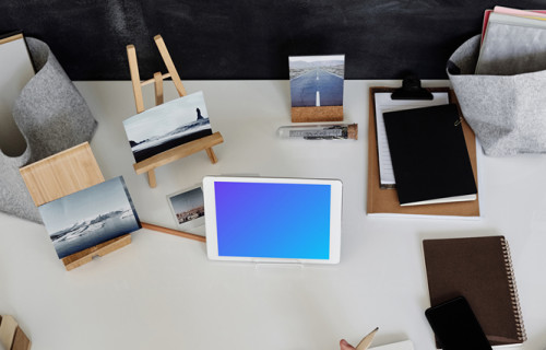 Young boy using an iPad mini on a table with a jotter by the side mockup