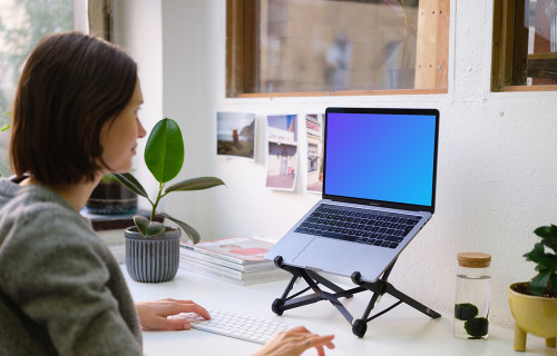 Young woman working on the Macbook Pro mockup in the bright office