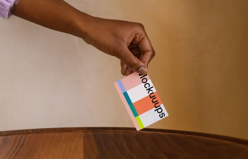 Business card mockup with hand over wooden surface