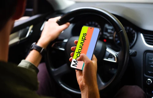 Driver tapping Samsung S20 mockup with hand on the wheel
