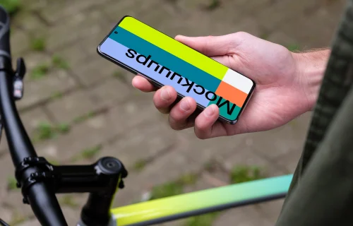 Holding Samsung S20 mockup in one hand next to a bike