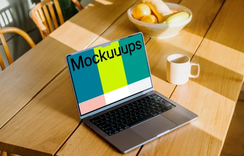 MacBook mockup beside a coffee mug and fruit basket