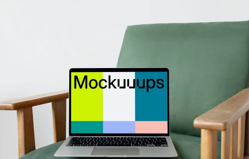 MacBook mockup on a green chair with wooden armrest