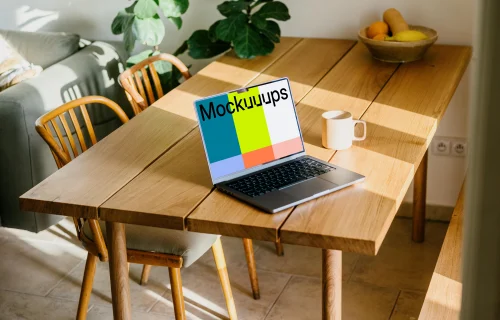 MacBook mockup on a table beside a coffee mug