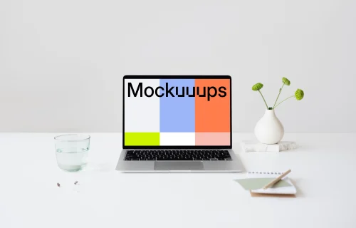 MacBook mockup on a table with glass of water at the side