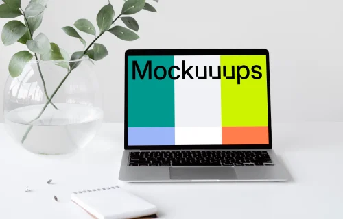 MacBook mockup on a white table with a bowl-shaped flower vase at the side