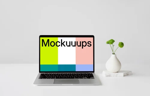 MacBook mockup on a white table with a fancy vase at the side
