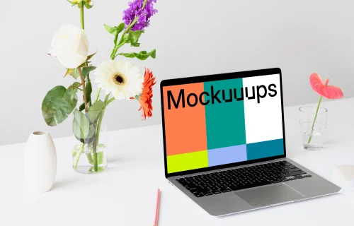 MacBook mockup on a white table with beautiful flowers in a transparent vase