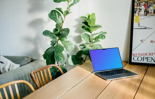 MacBook Pro mockup on a dining table beside a photo frame