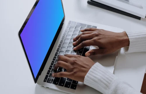 MacBook Pro mockup on a white table with glass of water at the side