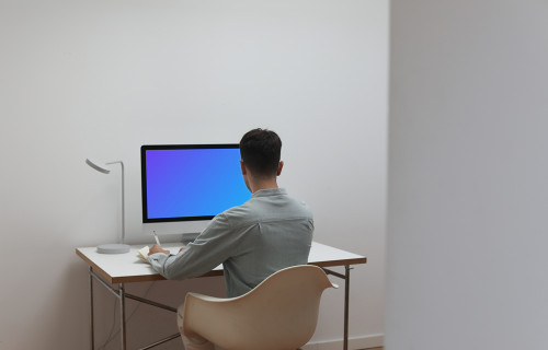 Man working on his iMac with his back to the camera
