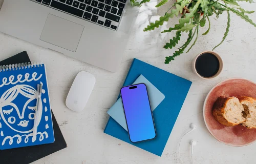 Top view of smartphone mockup next to MacBook and Magic Mouse
