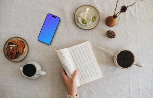 Top view of woman reading a book with smartphone on the side