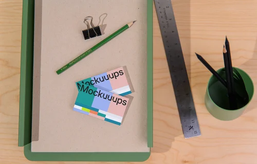 Two business card mockups on a desk with stationery