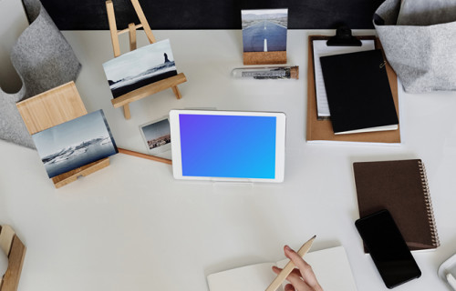 Young boy using an iPad mini on a table with a jotter by the side mockup