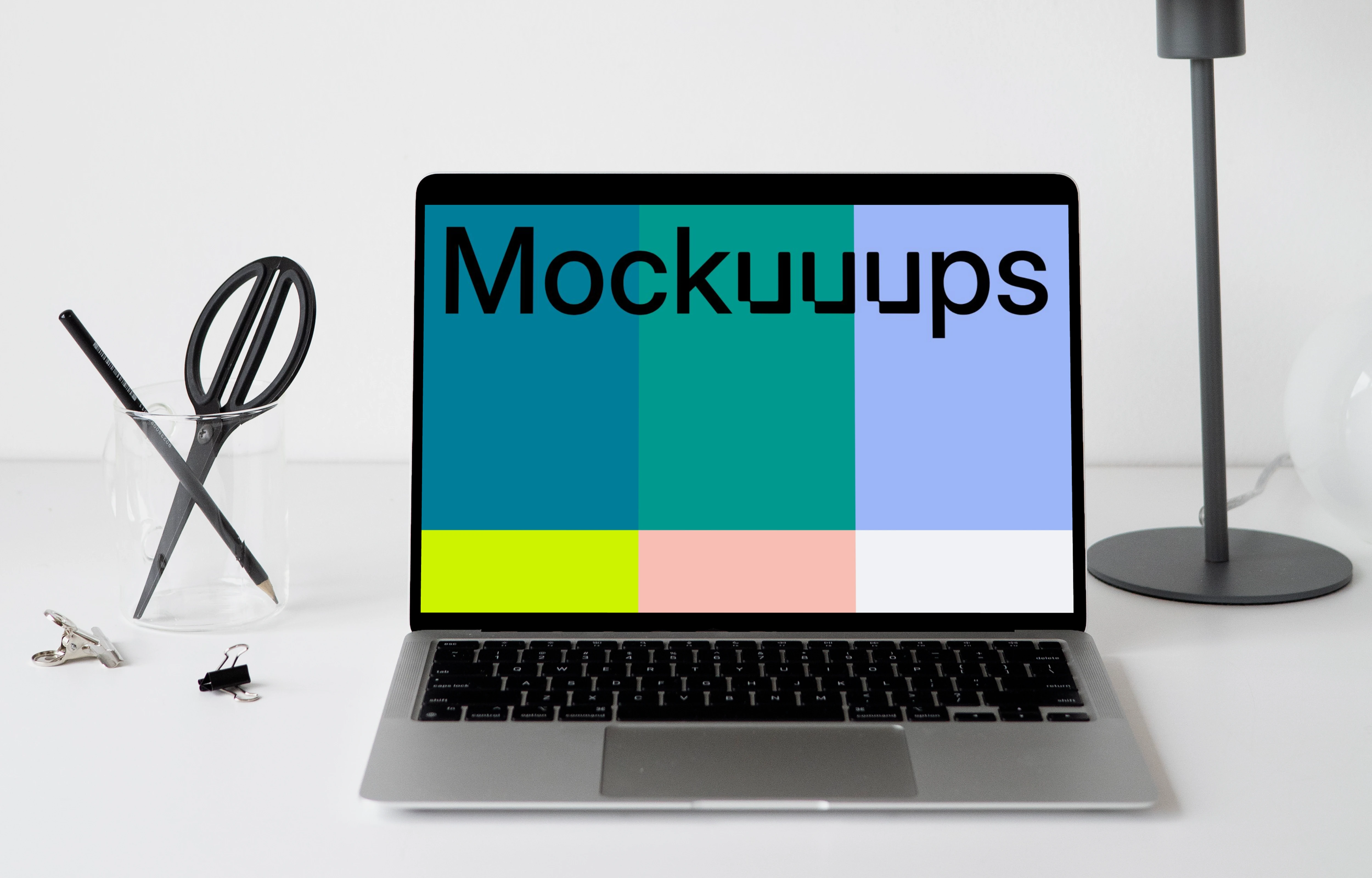 MacBook mockup on a white table with black table lamp at the side