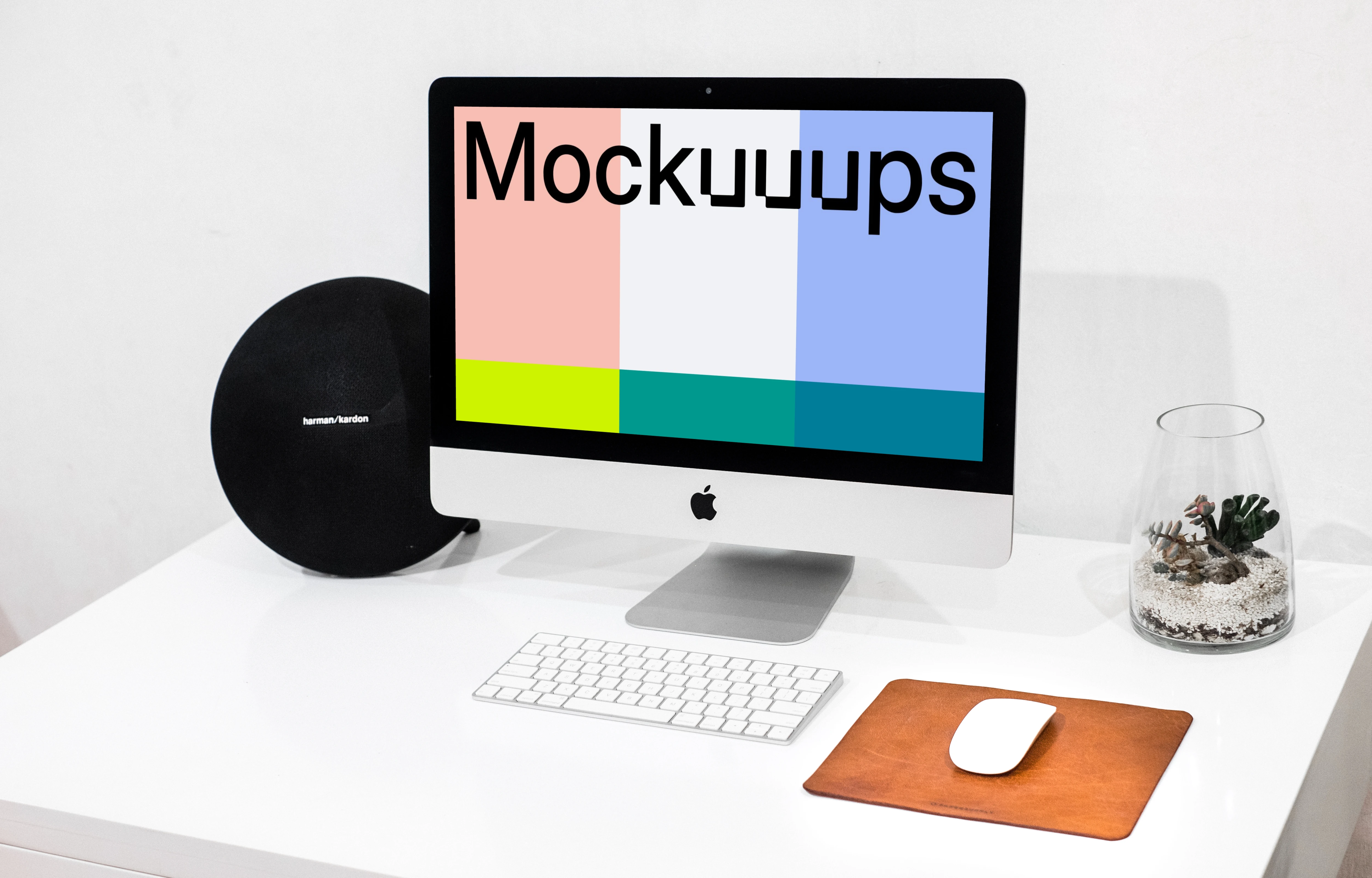 iMac mockup on a tidy work table beside a water vase