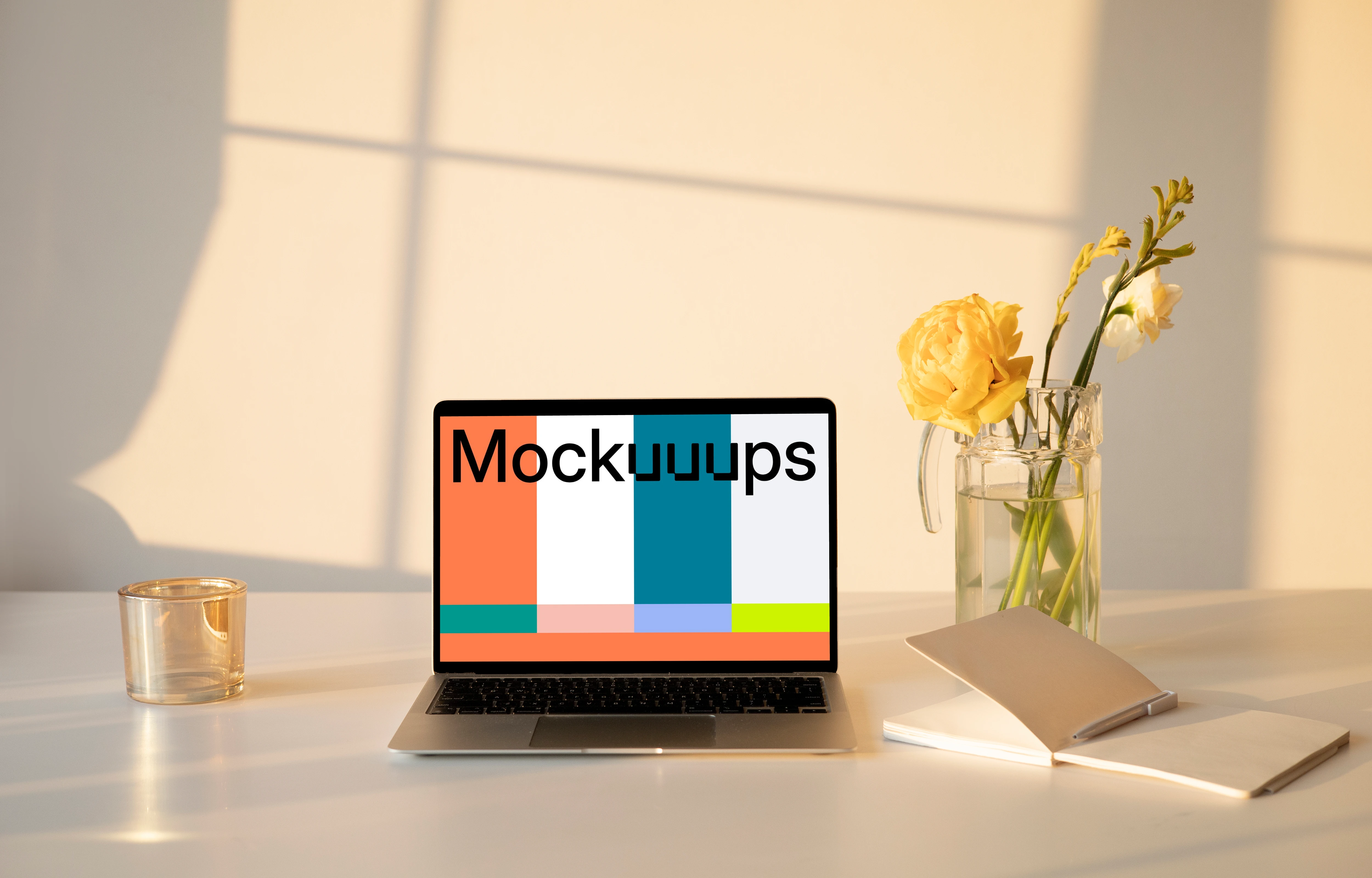MacBook mockup on a table with a flower vase and an exercise book at the side.