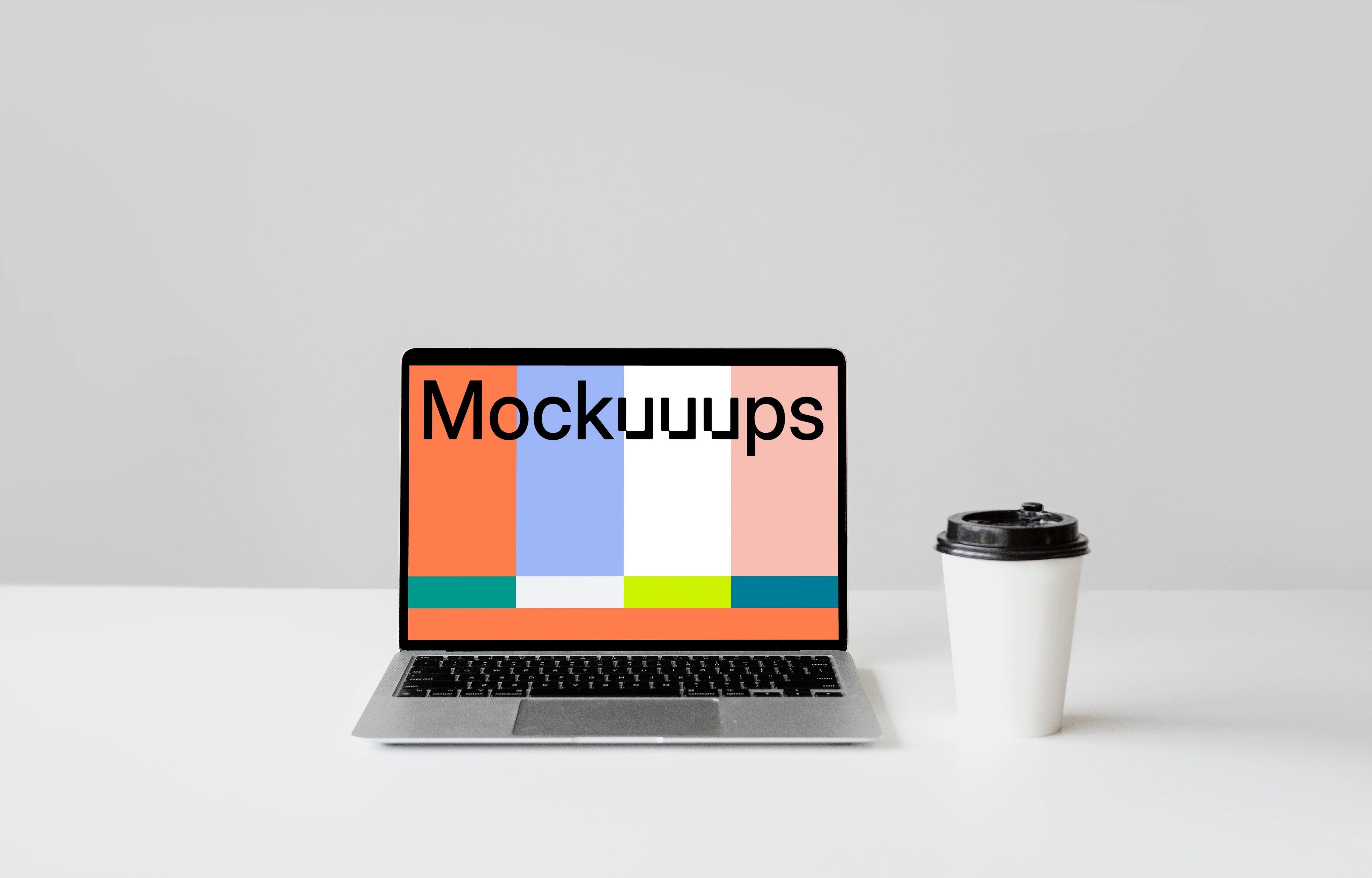MacBook mockup on a white table with a disposable coffee cup at the side