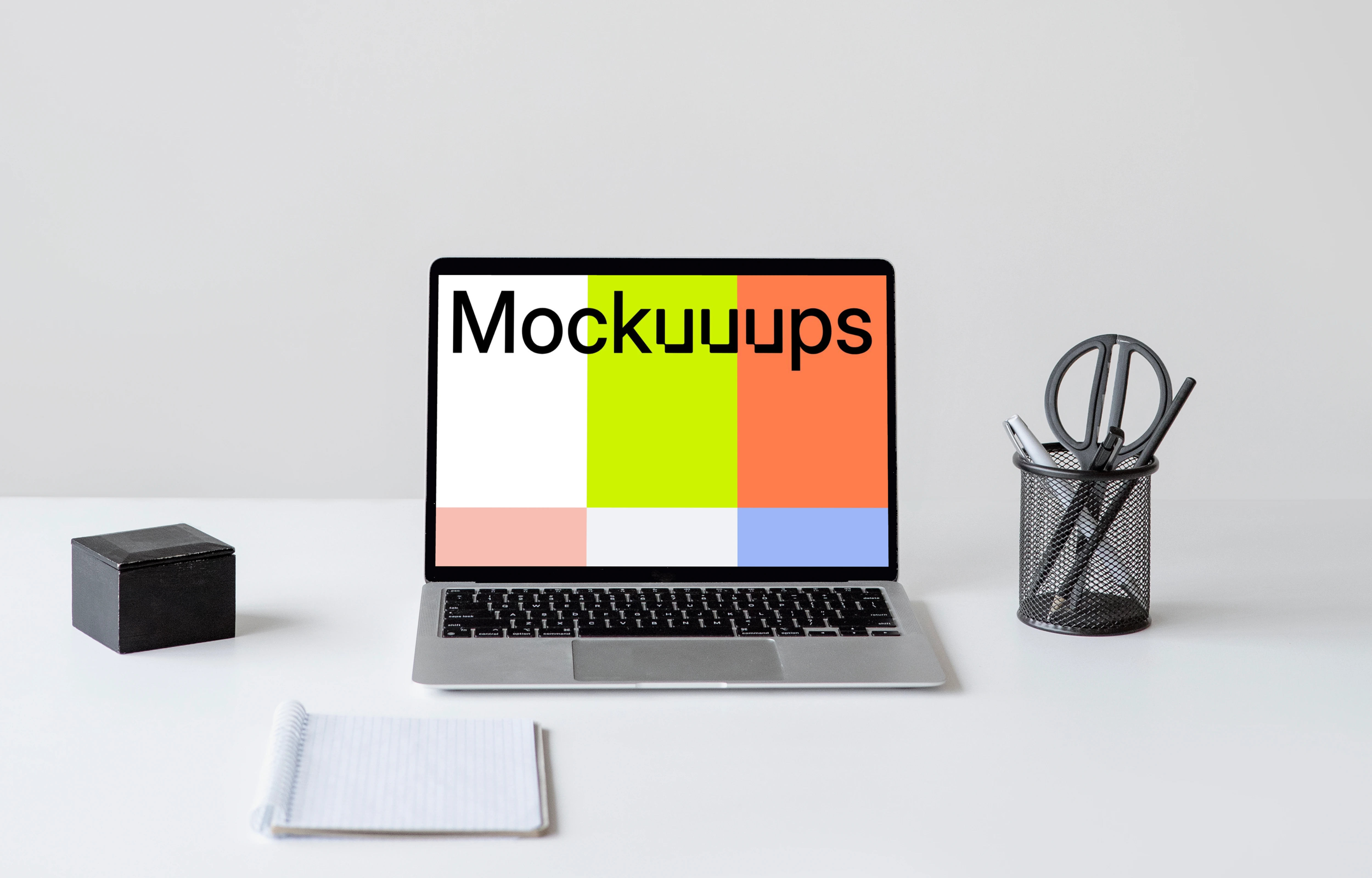 MacBook mockup on a white table with a notebook in front of it