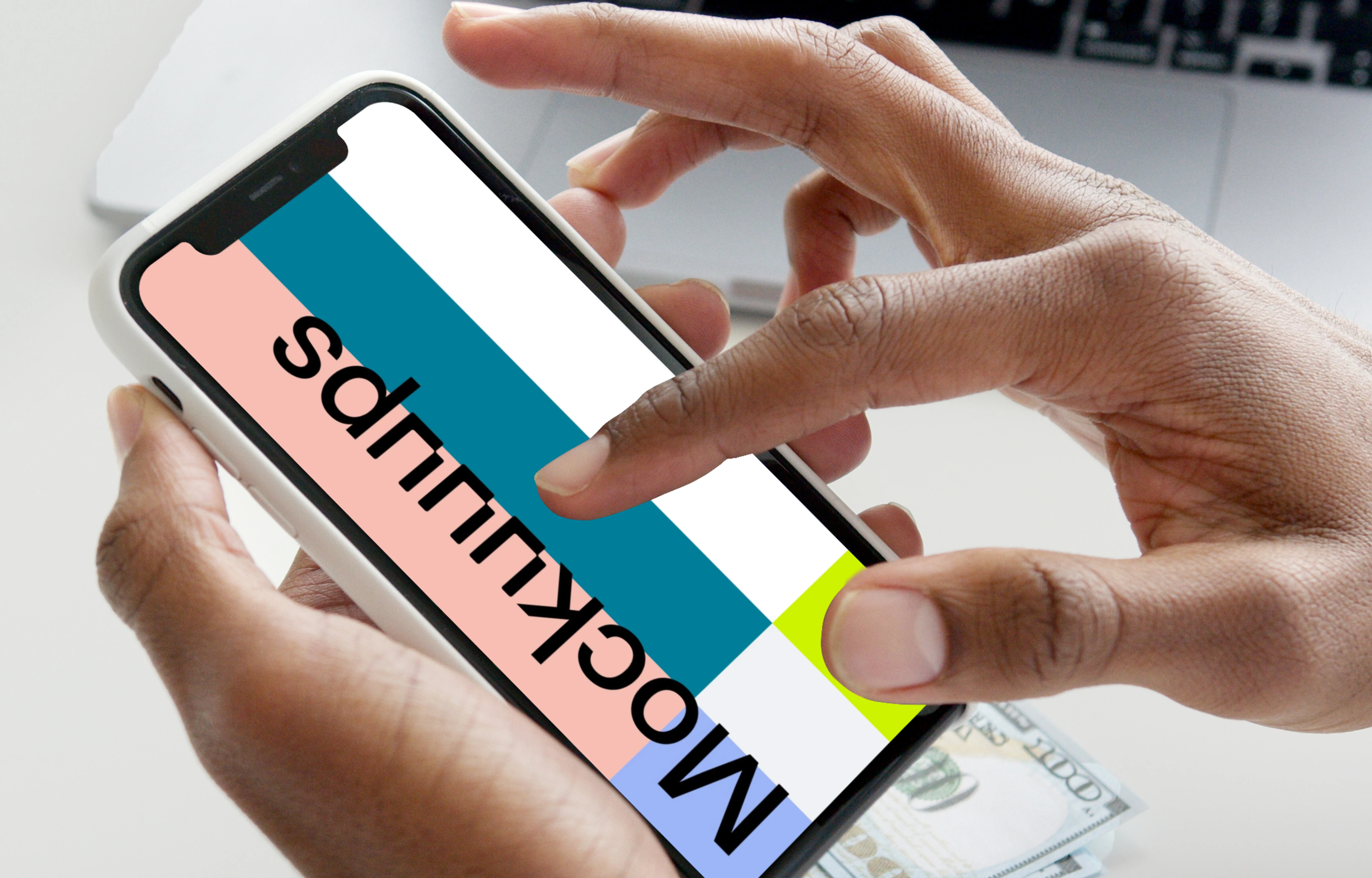 iPhone mockup in user’s hand with a MacBook