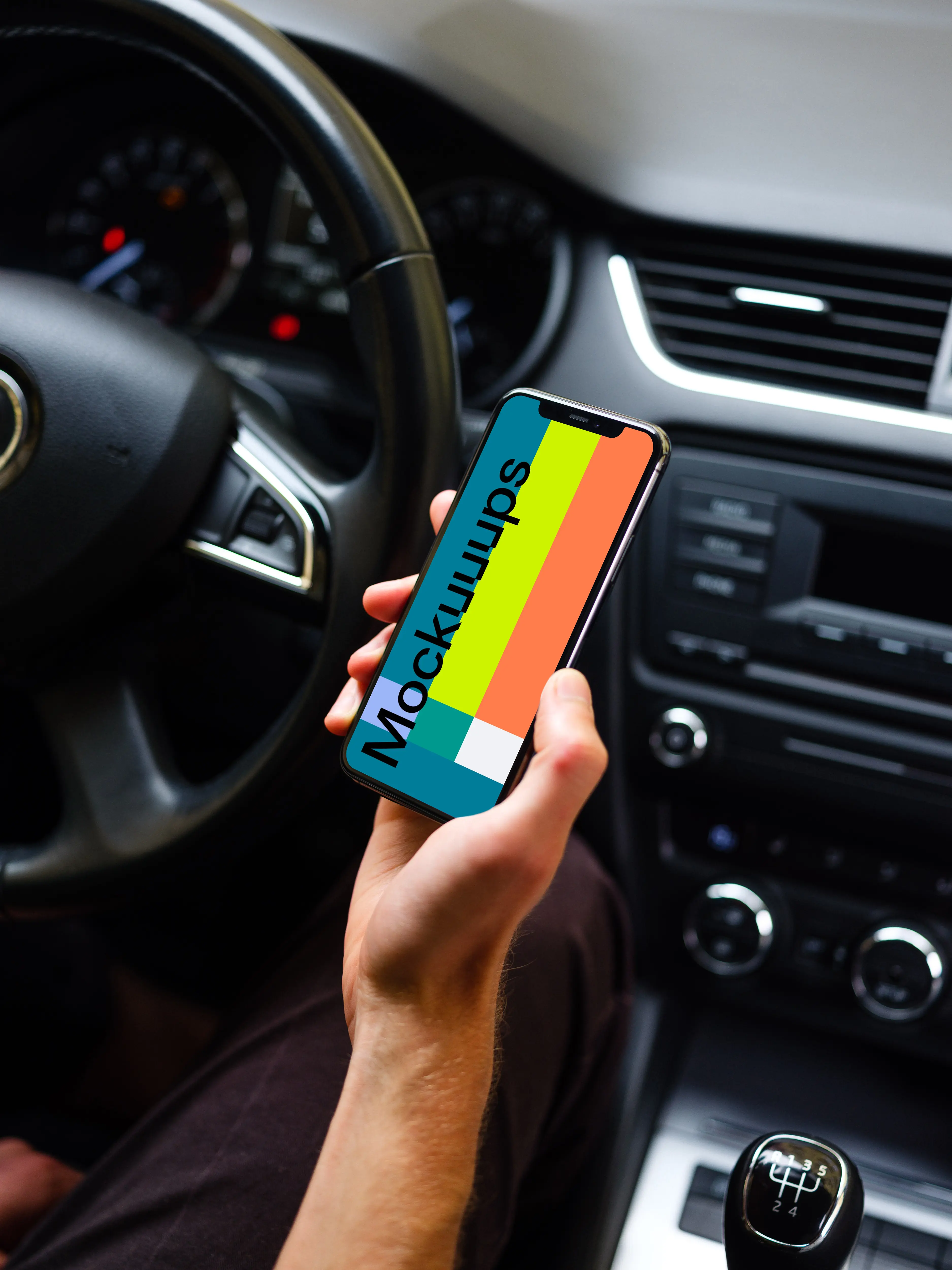 Drivers hand holding iPhone 11 mockup from behind the wheel