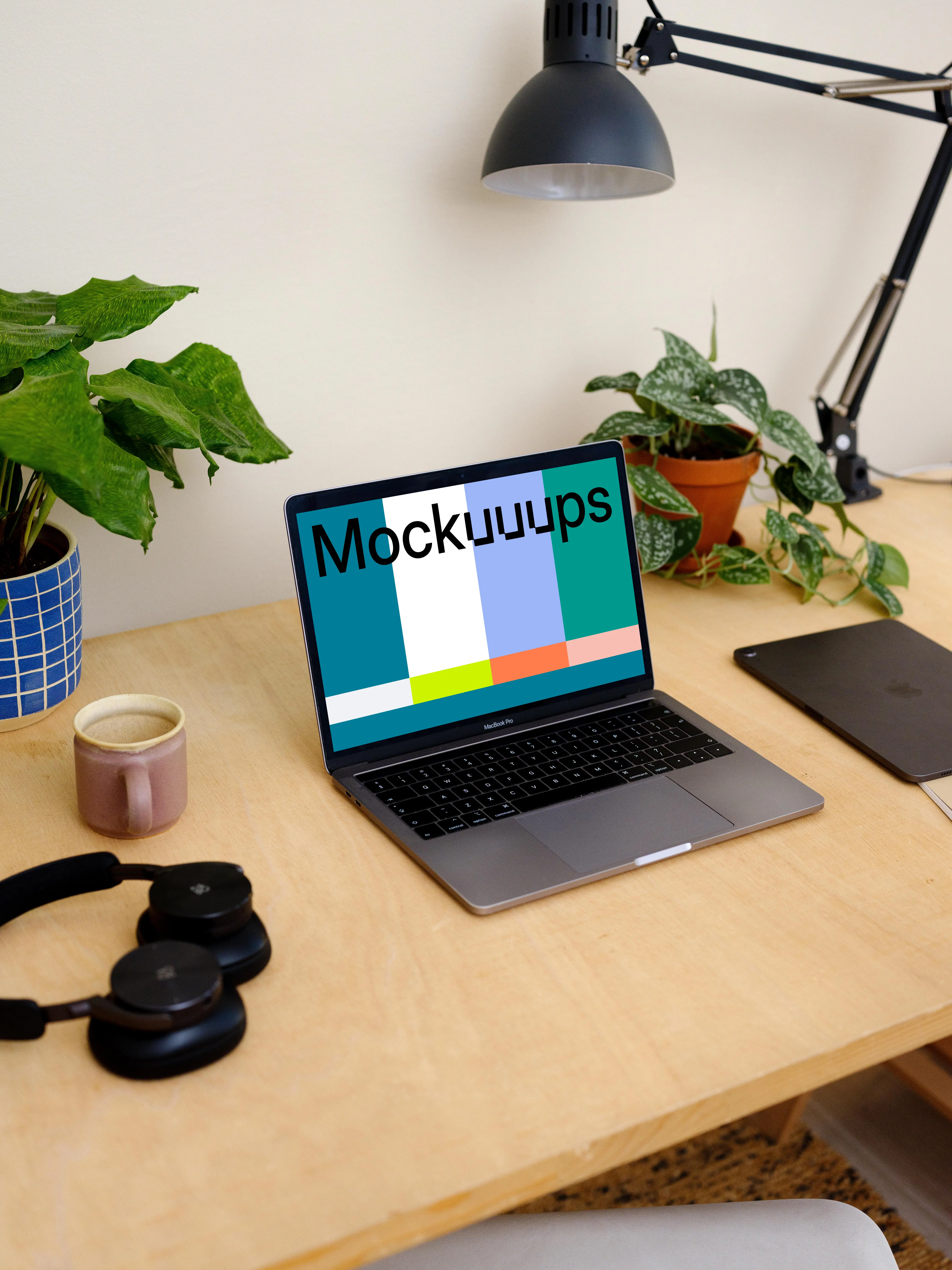 Grey MacBook Pro mockup with a coffee mug and an iPad at the side.