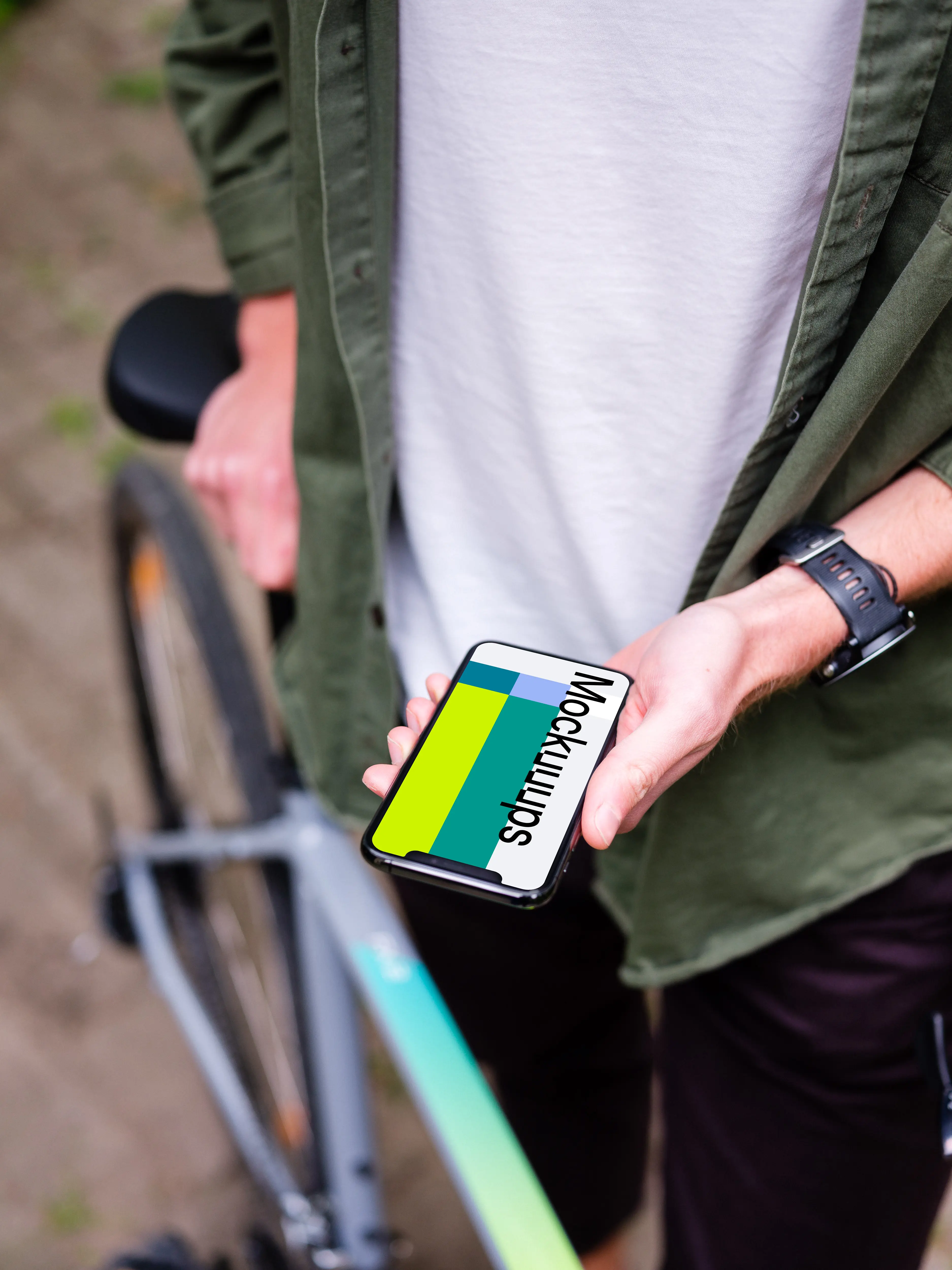 Holding an iPhone 11 Pro mockup whilst stood with a bike