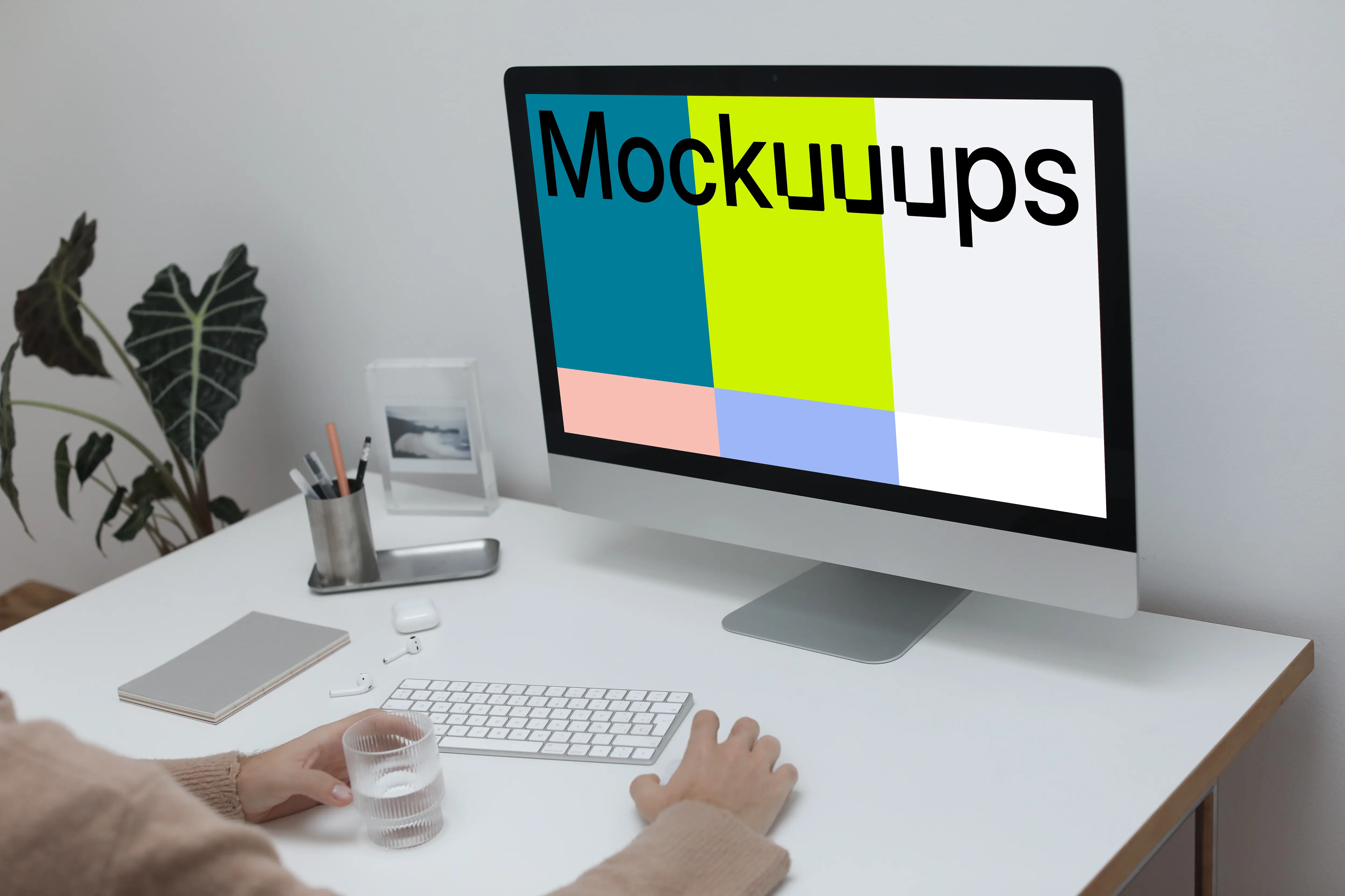 iMac on a white table with a cup of water