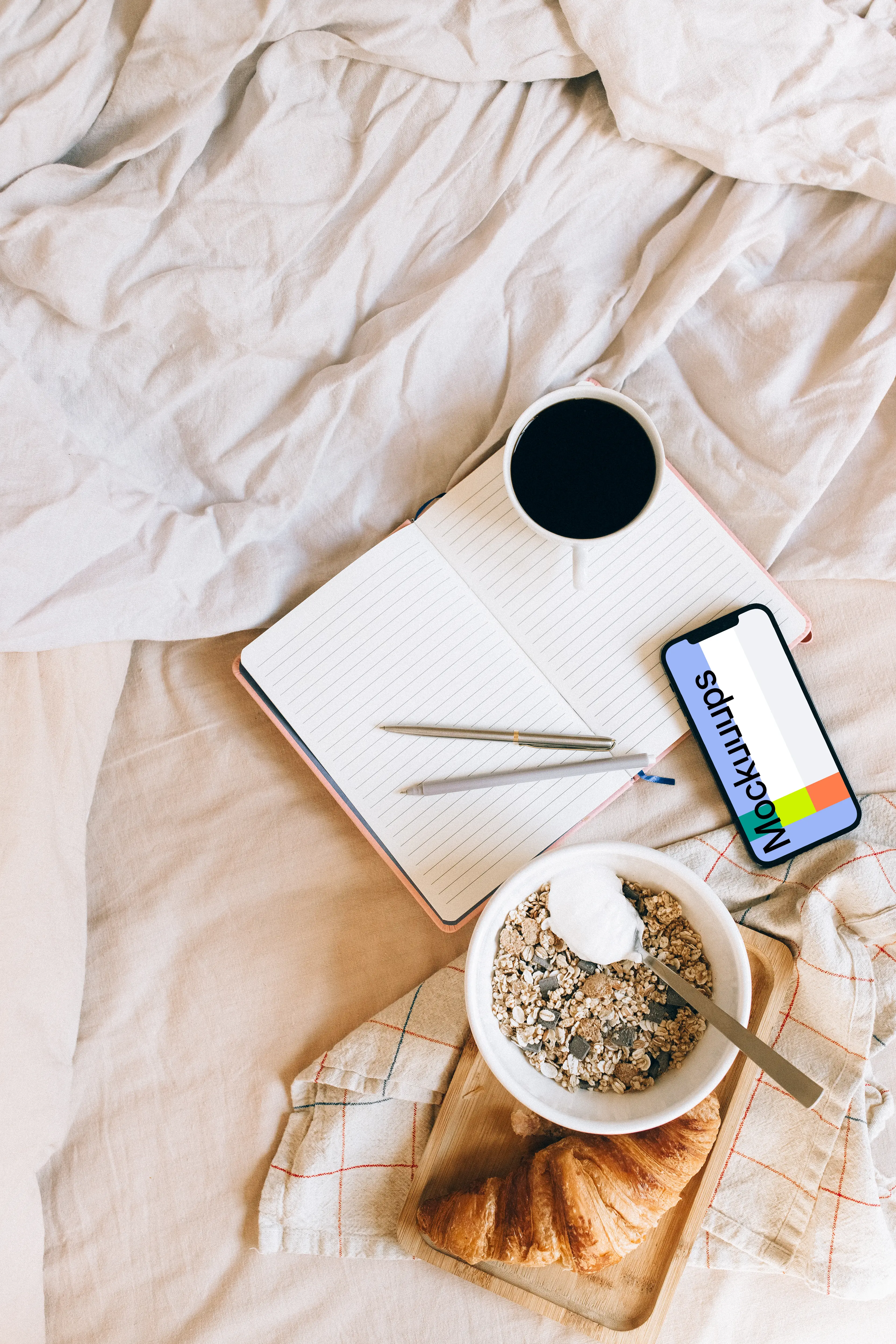 iPhone 12 Pro mockup on a bed, with a tray of food at its side