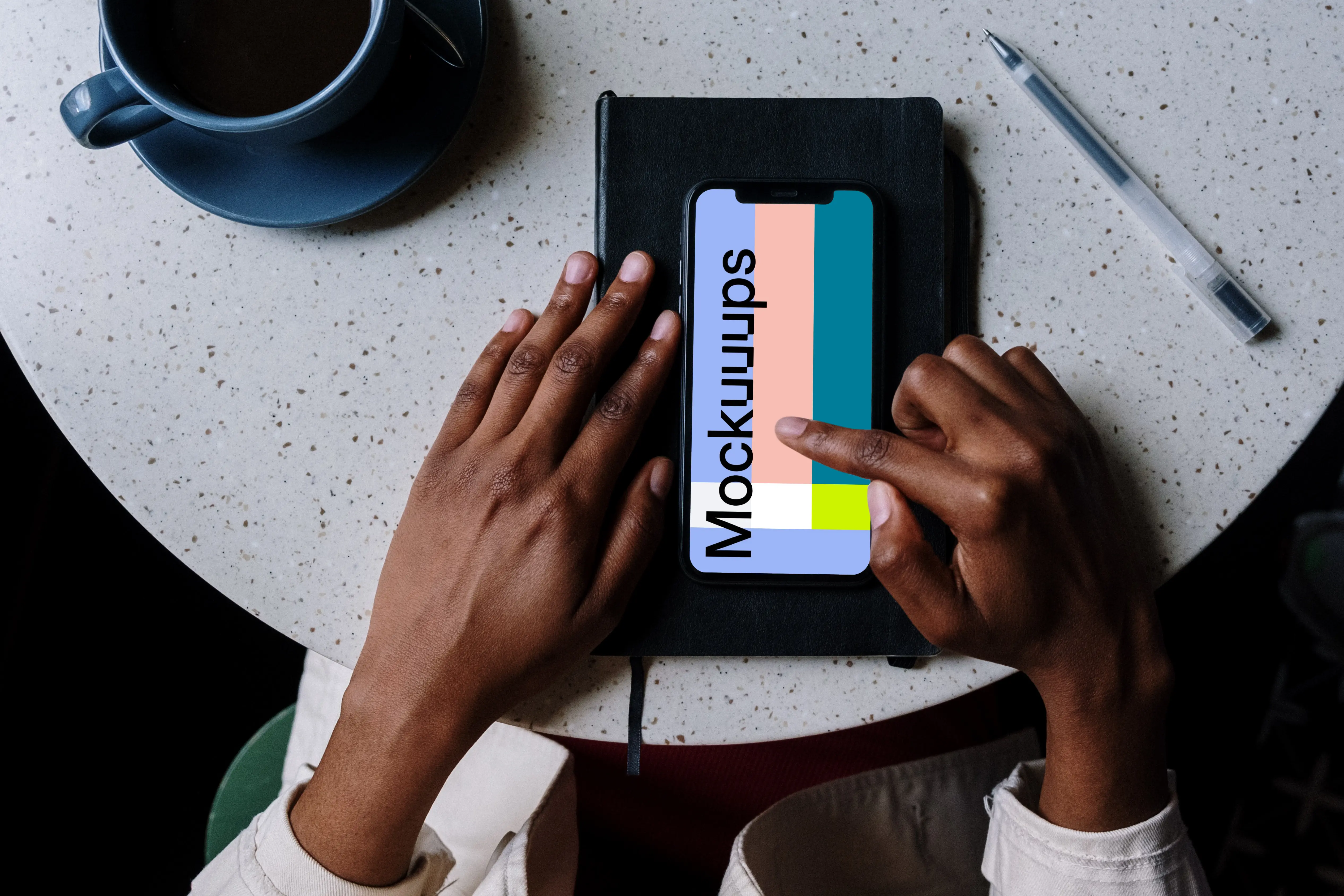 iPhone mockup on black notebook with pen by the side