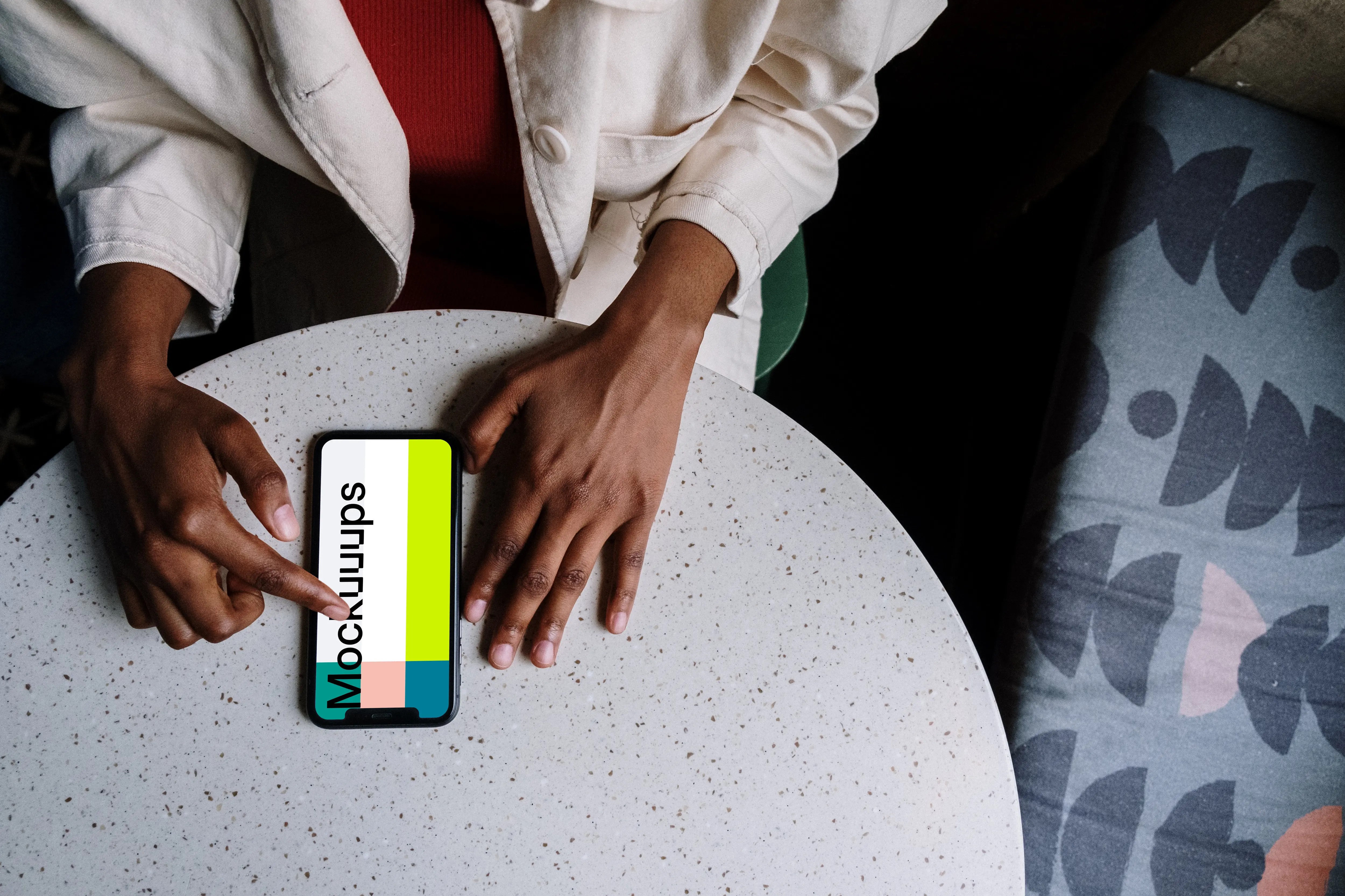 iPhone mockup on white table and a bed by the side