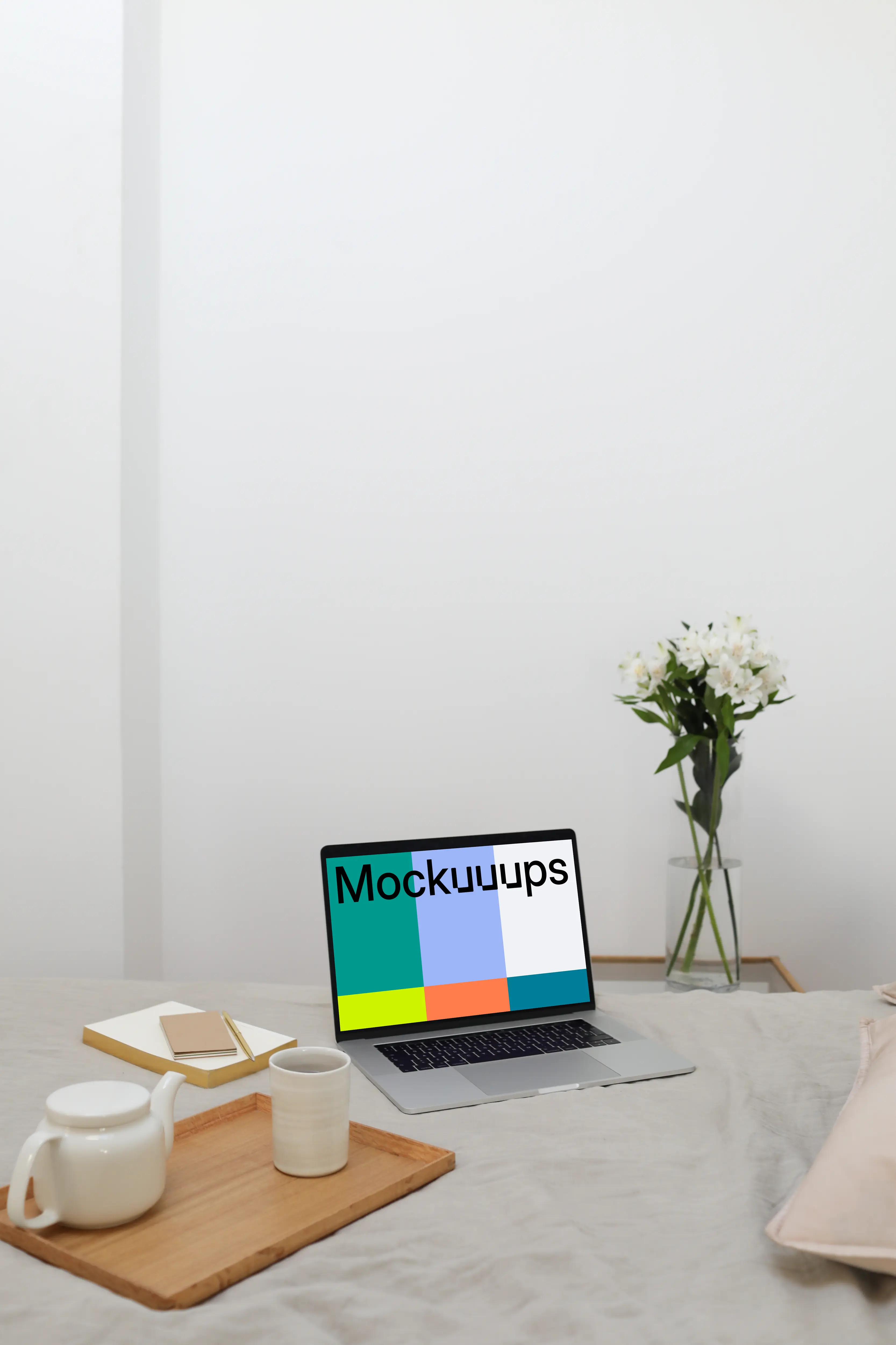 MacBook mockup on a bed with flower vase in the background