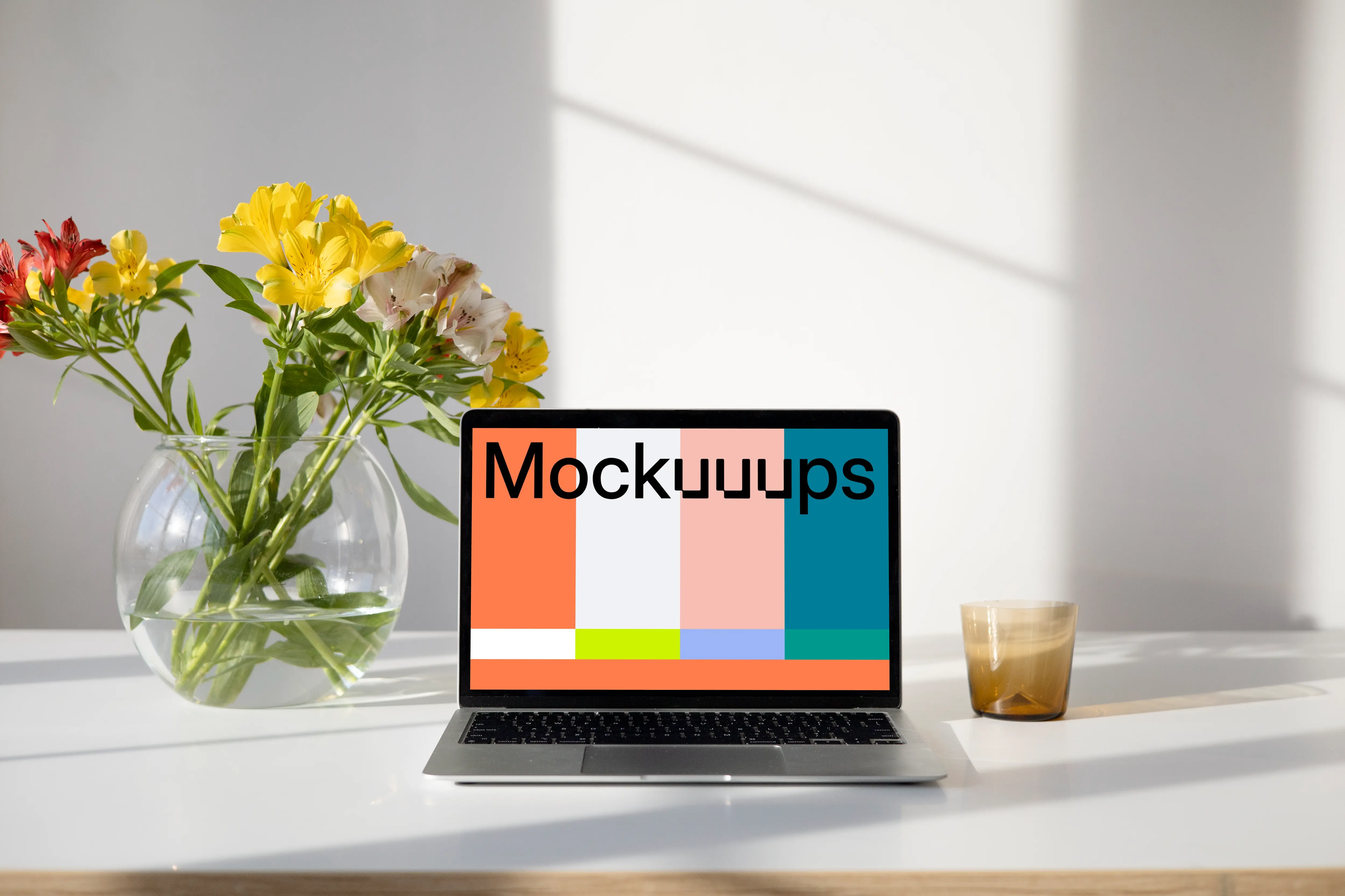 MacBook mockup on a table with flower vase containing water and beautiful flowers