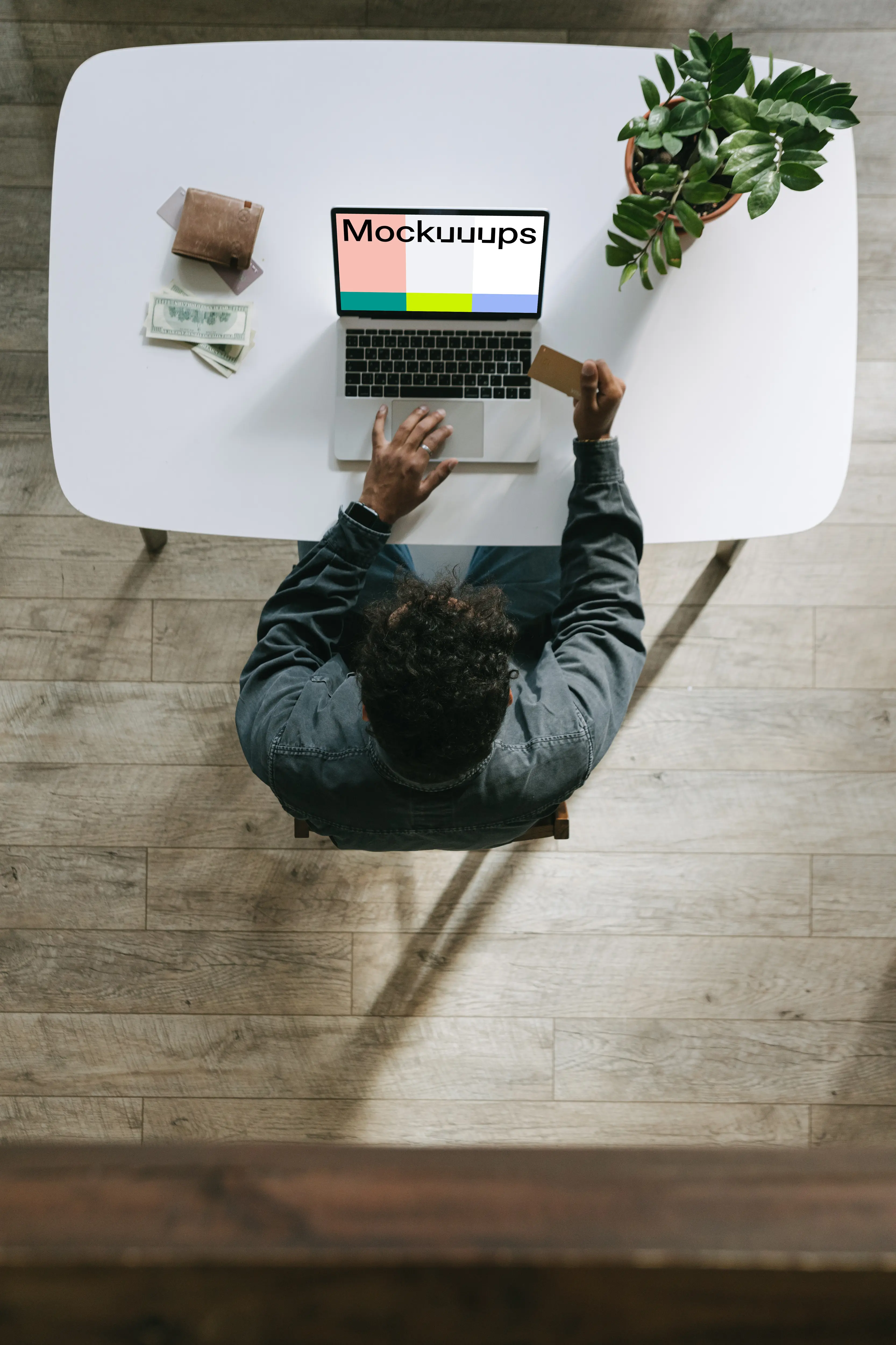 Mockup of man paying for an item on a grey MacBook beside a wallet.