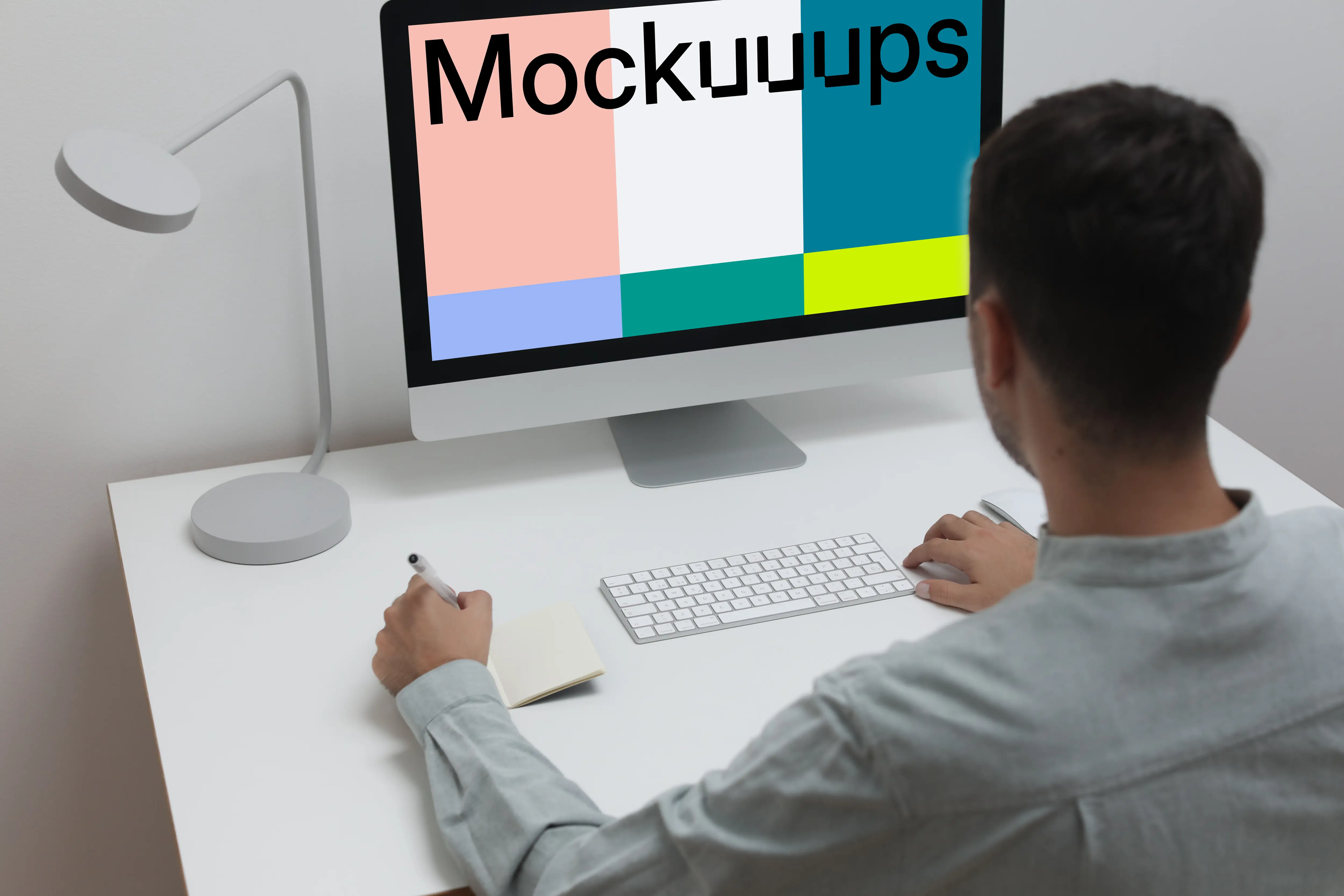 Mockup of man using iMac on a white table in a home office setting