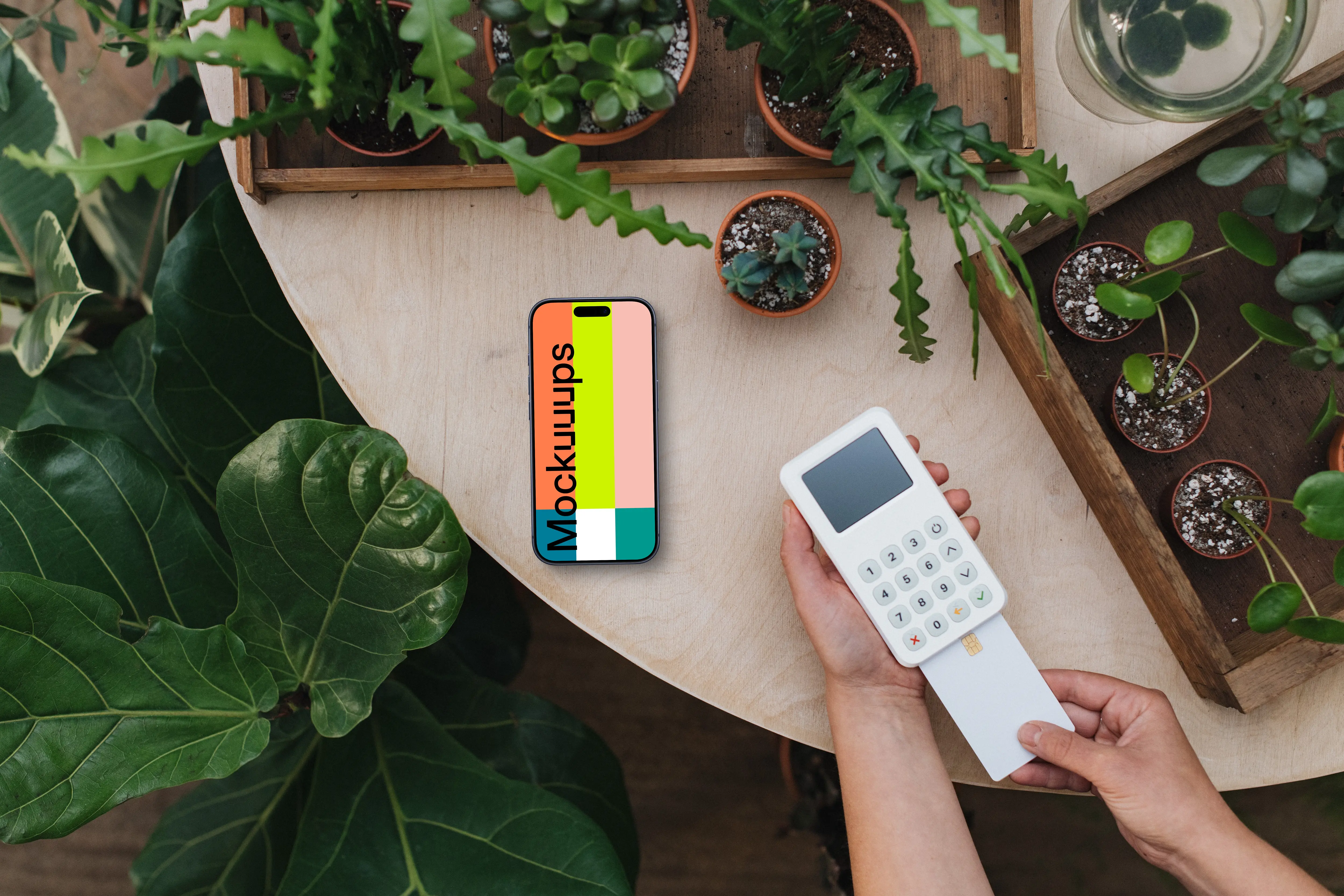 Payment terminal and an iPhone mockup surrounded by plants