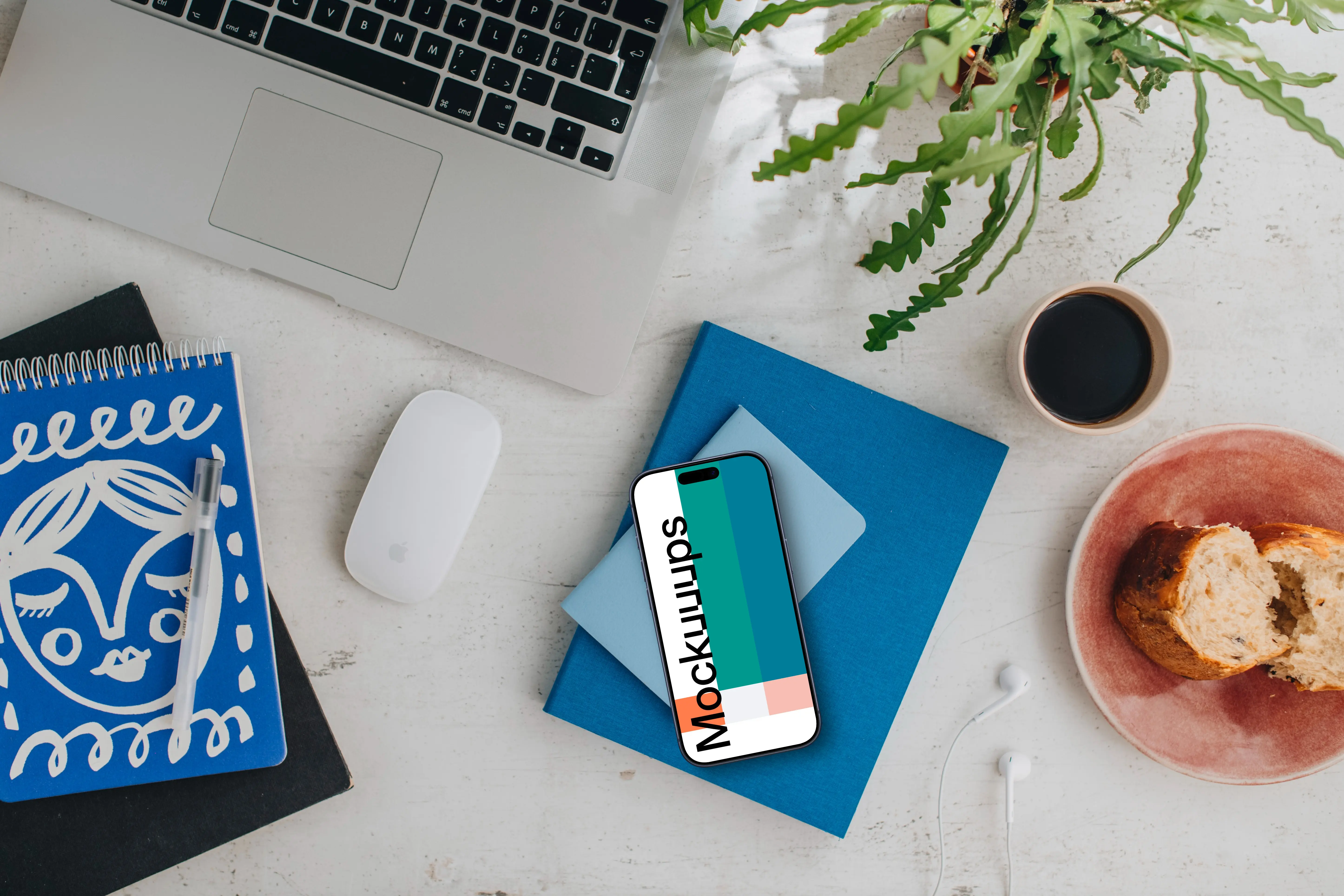 Top view of smartphone mockup next to MacBook and Magic Mouse