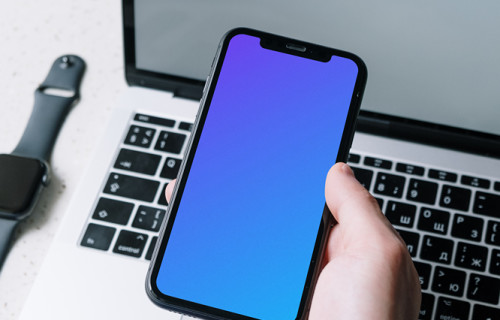 iPhone mockup sostenido sobre un MacBook por un usuario vestido de empresa