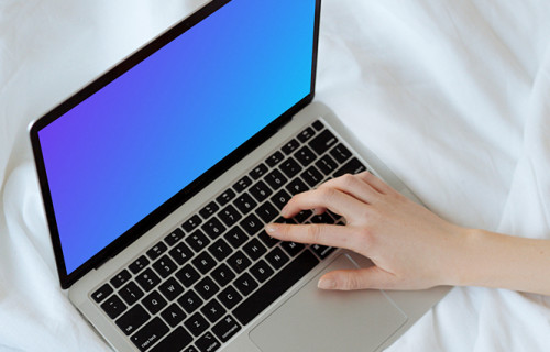 MacBook mockup on a white bed with a user typing on the laptop