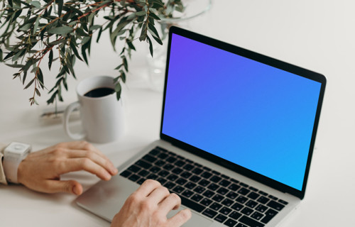 MacBook Pro mockup on a table with reading glasses by the side