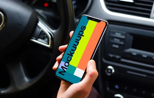 Drivers hand holding iPhone 11 mockup from behind the wheel