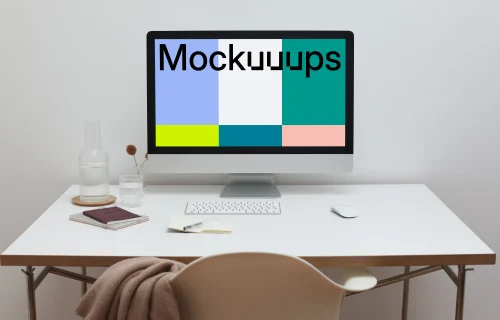 iMac mockup on a table with a jacket hanging on a chair in front of it