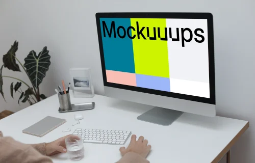 iMac on a white table with a cup of water